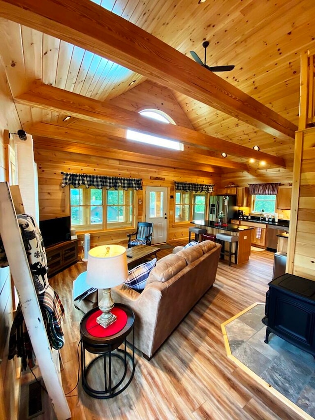 living room featuring wood walls, ceiling fan, a wealth of natural light, and light wood-type flooring