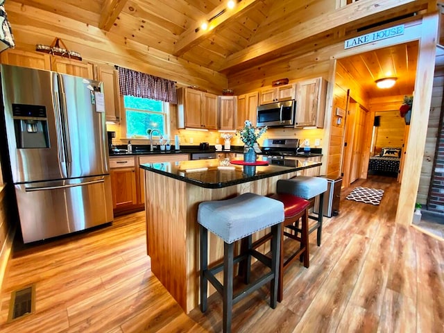 kitchen featuring light hardwood / wood-style floors, a center island, wood ceiling, a breakfast bar, and appliances with stainless steel finishes