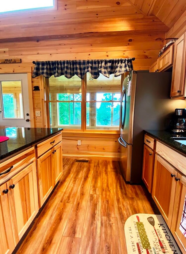 kitchen featuring stainless steel fridge, dark stone counters, lofted ceiling, wood ceiling, and light wood-type flooring