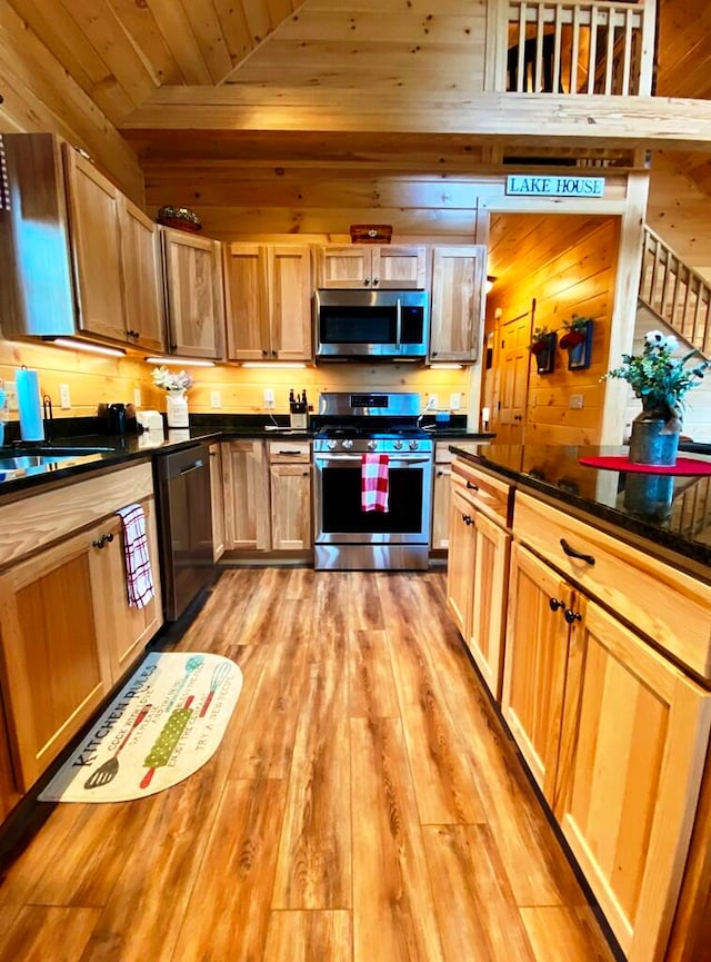 kitchen featuring stainless steel appliances, wood walls, light hardwood / wood-style floors, sink, and wood ceiling