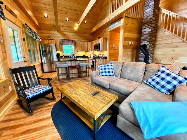 living room featuring lofted ceiling with beams, light hardwood / wood-style floors, and wooden walls