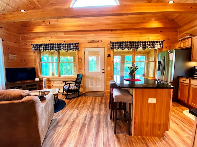 kitchen featuring wooden ceiling, light hardwood / wood-style floors, a kitchen island, a breakfast bar area, and vaulted ceiling