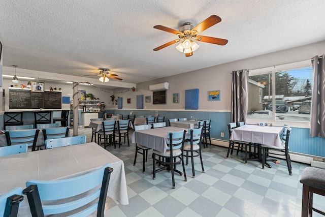 dining space featuring tile patterned floors, ceiling fan, a baseboard radiator, a wall mounted air conditioner, and wainscoting