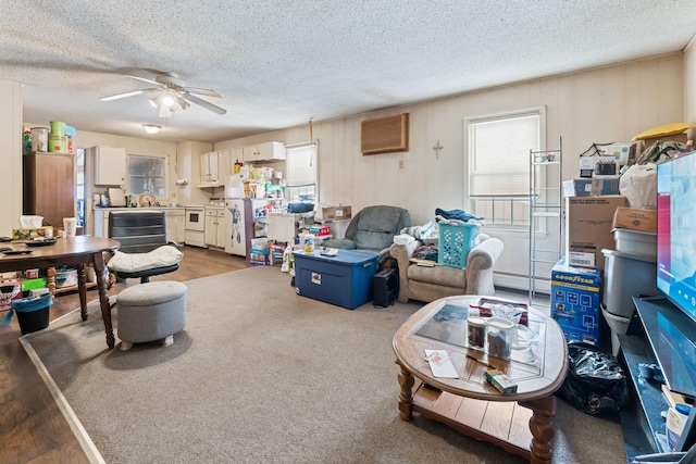living area with a textured ceiling, a baseboard heating unit, and a ceiling fan