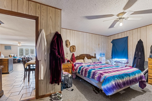 bedroom with a textured ceiling, ceiling fan, and wooden walls