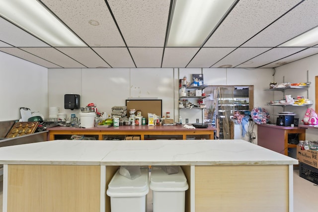 kitchen with a drop ceiling and light stone counters
