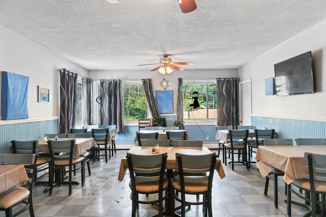 dining room featuring a wainscoted wall, tile patterned floors, a textured ceiling, and ceiling fan