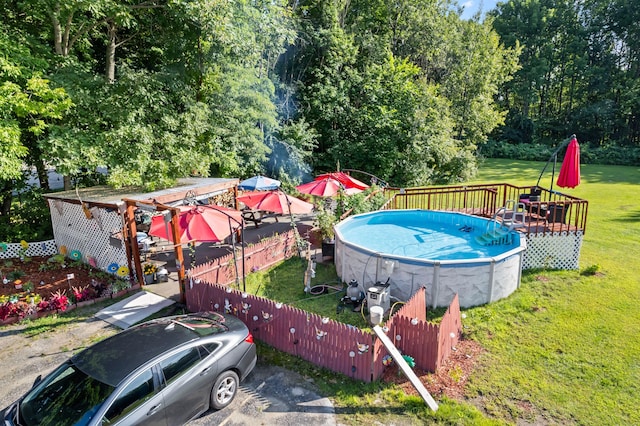 view of swimming pool with a lawn, a fenced in pool, a wooden deck, and fence