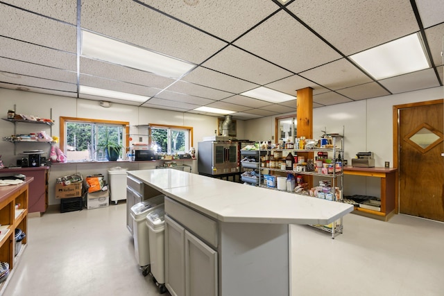 kitchen with gray cabinetry, a drop ceiling, and a center island