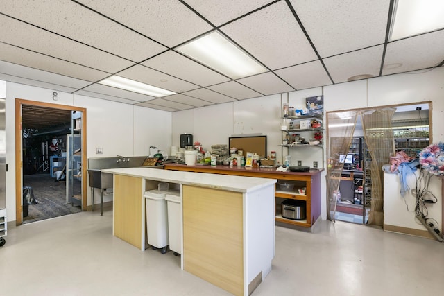 kitchen with light countertops, a paneled ceiling, and a kitchen island