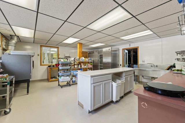 kitchen with a center island, light countertops, and a drop ceiling