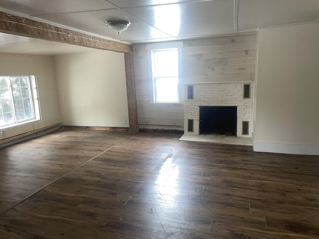 unfurnished living room featuring a brick fireplace and dark hardwood / wood-style flooring