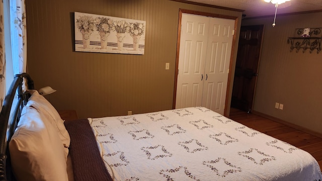 bedroom with a closet, dark hardwood / wood-style flooring, and crown molding