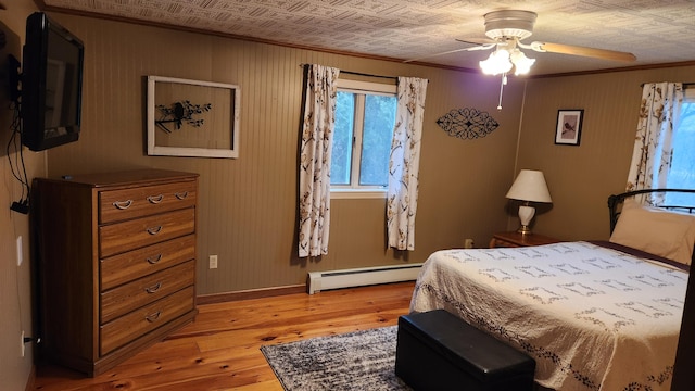 bedroom with baseboard heating, ceiling fan, and light hardwood / wood-style flooring