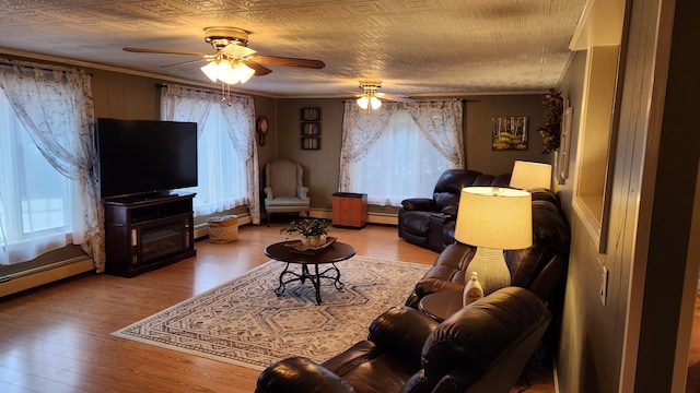 living room featuring ceiling fan, a textured ceiling, a baseboard heating unit, ornamental molding, and hardwood / wood-style flooring