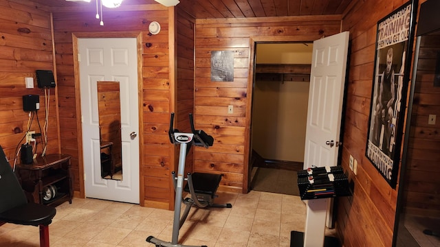 exercise area with wooden ceiling, wooden walls, ceiling fan, and light tile floors