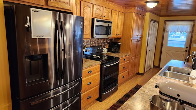 kitchen with light hardwood / wood-style flooring, appliances with stainless steel finishes, light stone counters, backsplash, and sink