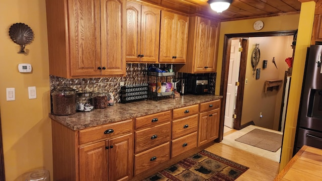 kitchen with stainless steel refrigerator with ice dispenser, backsplash, and light tile floors