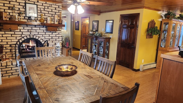 dining space featuring light hardwood / wood-style flooring, a fireplace, baseboard heating, and wooden ceiling