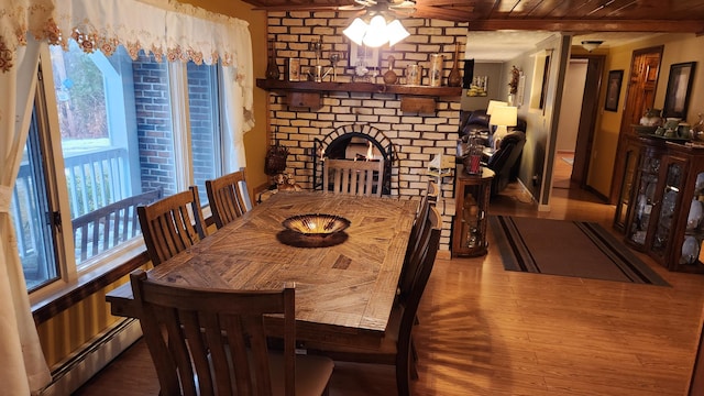 dining room with a fireplace, ceiling fan, hardwood / wood-style floors, and baseboard heating