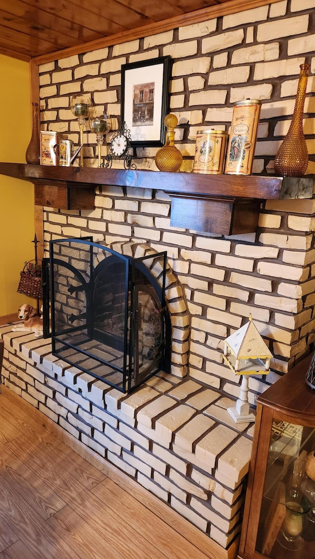 room details with wooden ceiling, a brick fireplace, and hardwood / wood-style floors