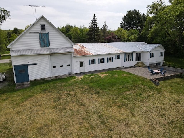 rear view of property featuring a garage, a patio area, and a lawn