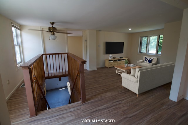 living room with dark hardwood / wood-style flooring, ceiling fan, and plenty of natural light