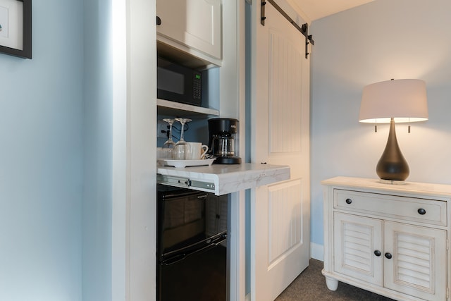 kitchen with a barn door, dark carpet, and black microwave