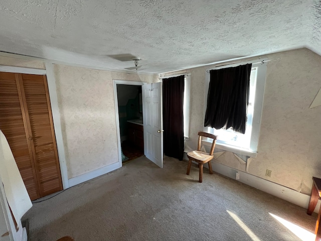 unfurnished bedroom with vaulted ceiling, a textured ceiling, carpet floors, and a closet