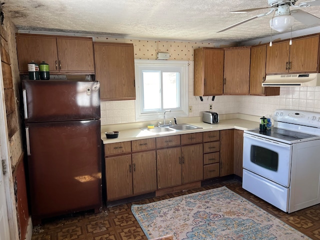 kitchen featuring electric stove, ceiling fan, a textured ceiling, refrigerator, and sink