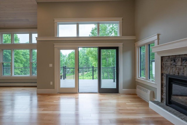 862 W Neck Rd, Nobleboro, ME 04555 - entryway with a baseboard heating unit, a stone fireplace, an AC wall unit, and light wood-style floors