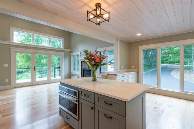 862 W Neck Rd, Nobleboro, ME 04555 - kitchen with gray cabinets, wooden ceiling, oven, light wood-type flooring, and a glass covered fireplace