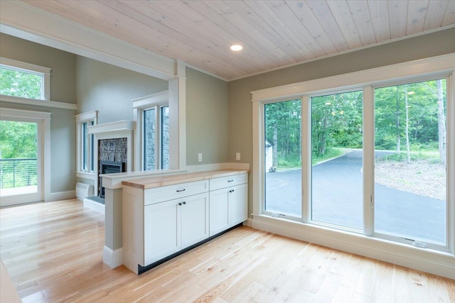 862 W Neck Rd, Nobleboro, ME 04555 - kitchen featuring a fireplace, white cabinetry, wood ceiling, light countertops, and light wood-type flooring