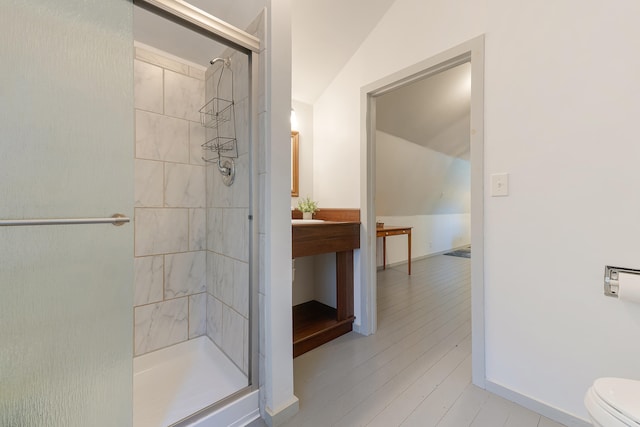 bathroom featuring a shower with door, wood-type flooring, toilet, and vaulted ceiling