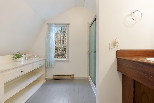 bathroom featuring baseboard heating, a shower with door, vanity, hardwood / wood-style floors, and vaulted ceiling