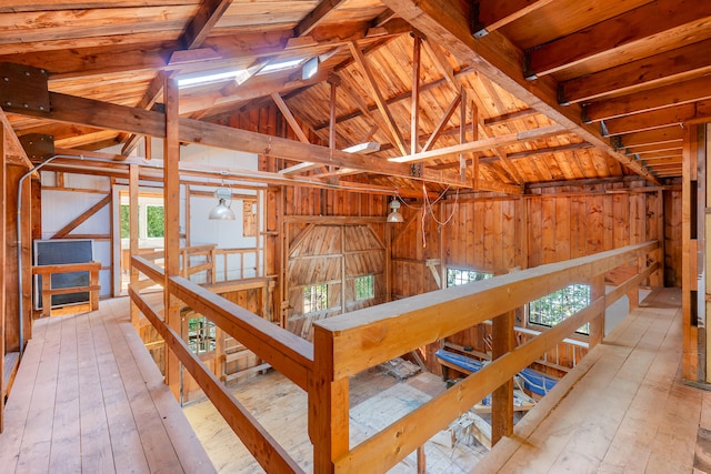 miscellaneous room featuring lofted ceiling, light hardwood / wood-style floors, and wooden walls