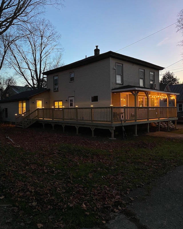 back house at dusk featuring a deck