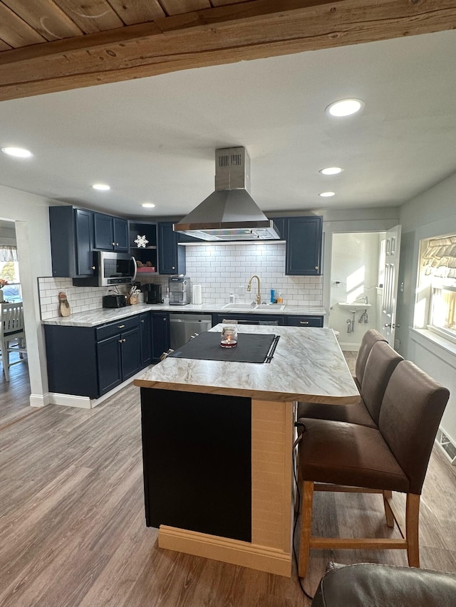 kitchen featuring wall chimney range hood, tasteful backsplash, appliances with stainless steel finishes, and light hardwood / wood-style flooring