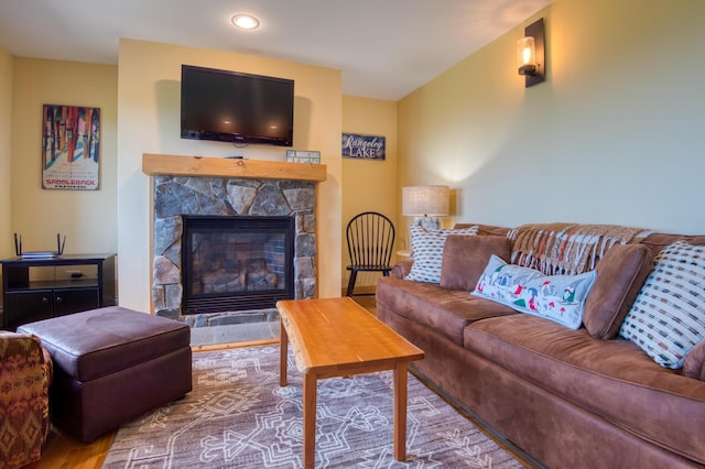 living area featuring a stone fireplace and wood finished floors