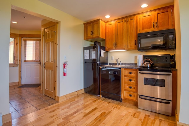 kitchen featuring black appliances, brown cabinetry, dark countertops, and light wood finished floors