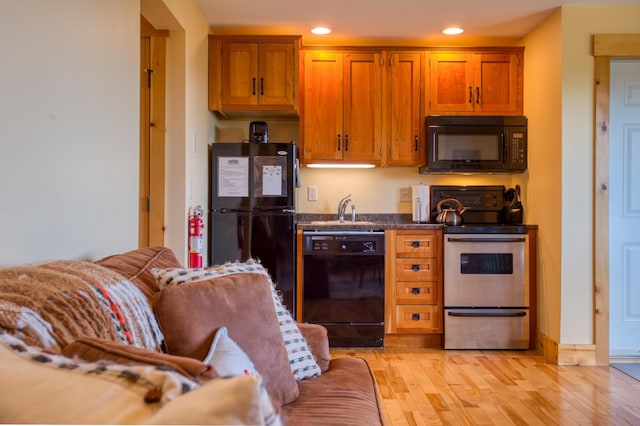 kitchen featuring brown cabinetry, recessed lighting, a sink, black appliances, and light wood-type flooring