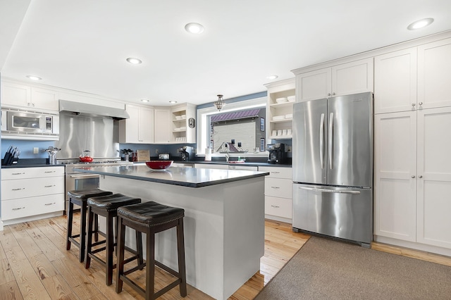 kitchen featuring light wood-type flooring, white cabinetry, a center island, a kitchen breakfast bar, and stainless steel appliances