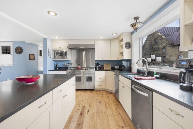 kitchen with sink, appliances with stainless steel finishes, light hardwood / wood-style floors, and range hood