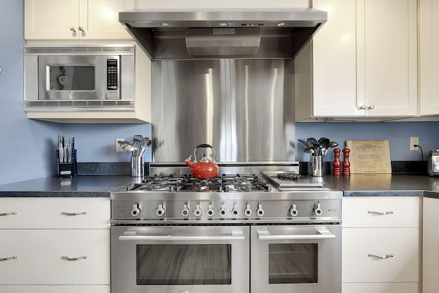 kitchen featuring wall chimney range hood, stainless steel appliances, and white cabinets