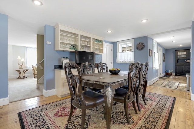 dining room with a baseboard heating unit, a healthy amount of sunlight, and light hardwood / wood-style flooring