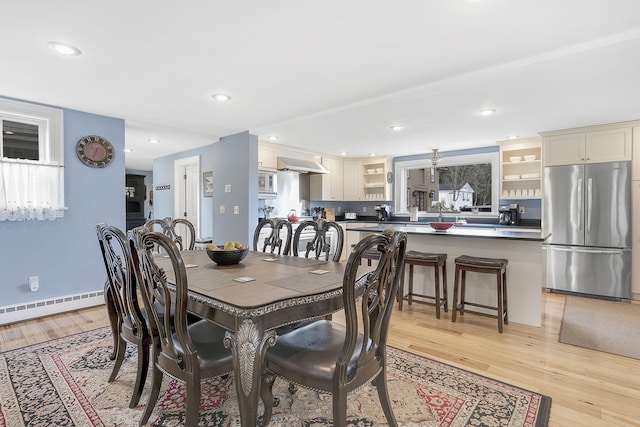 dining area with light wood-type flooring and baseboard heating