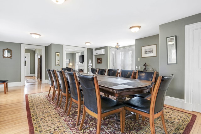 dining area with a wall mounted AC and light hardwood / wood-style floors