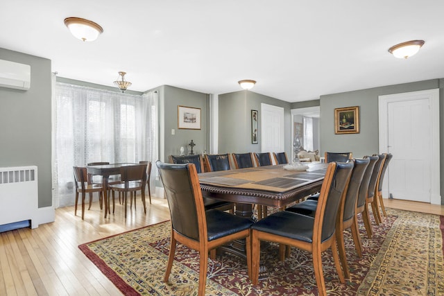 dining room with radiator, a wall mounted AC, and hardwood / wood-style flooring