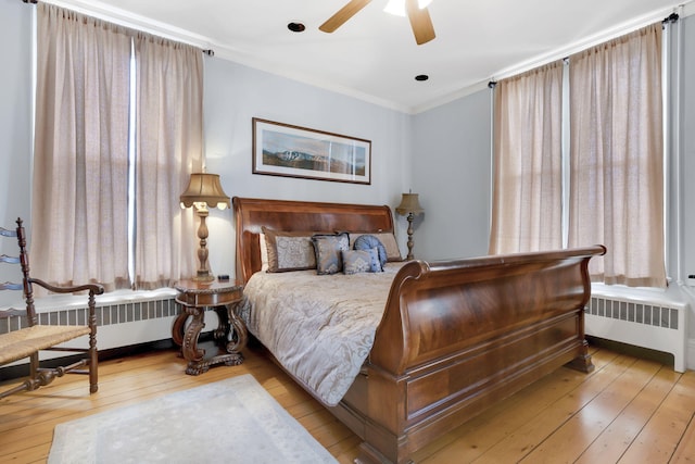 bedroom featuring light wood-type flooring, crown molding, and radiator heating unit