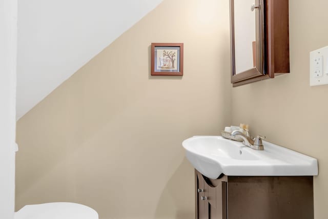 bathroom featuring vanity, vaulted ceiling, and toilet